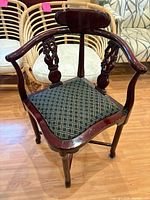 Front view of carved dark wood corner chair with upholstered seat