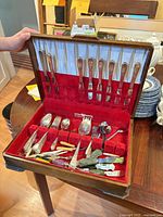 Chest open showing dinner knives and assorted flatware inside