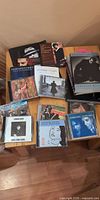 Overview of CDs and books spread on small table, multiple Leonard Cohen titles visible