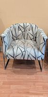 Front view of upholstered armchair showing pattern, tufted back, chrome legs