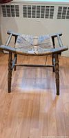Overall view of wooden frame stool with damaged woven rattan seat