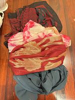 Stack of four different coloured and patterned scarves on wooden surface