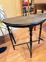 Full view of demilune wooden side table with turned legs