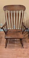 Front view of solid wood rocking chair showing spindle back, arms and seat