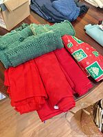 Stack of green ribbed placemats and red Christmas tablecloths on table