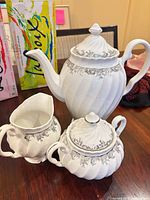 Front view of teapot, sugar bowl, creamer showing design and trim