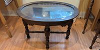 Full view of oval coffee table showing glass inset and wooden frame