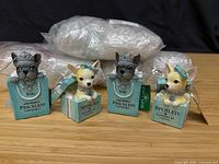 Four sample puppy ornaments, two French bulldog style and two Chihuahua style, bubble-wrapped extras in background