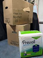 Two cardboard boxes marked 4 bags of 15 each and one visible sealed pack of Prevail NU-FIT Daily Briefs