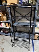 Front view of black collapsible metal wire rack with five shelves on casters
