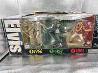 Front of damaged box showing all three Elvis figures dated 1956, 1957, 1961