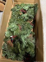 Garland in box showing evergreen branches, berries, pinecones