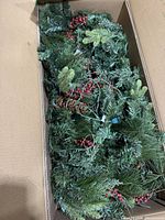 Garland inside box showing mixed greenery, berries, wiring