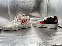 Pair of Adidas Dame Time sneakers side view showing mismatched colors