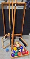 overall lot with cue stand, cues, triangle rack, balls, brush, chalk