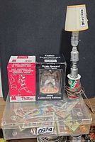 Group shot of all items: two boxed bobbleheads, Canada Dry Stanley Cup lamp with shade, clear bin of sports cards