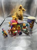 Group shot showing all items: plush kangaroo with joey, ceramic Pooh heart vase, metal canister, and assorted ornaments