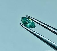 Close-up of marquise Alexandrite held in tweezers showing overall shape and color
