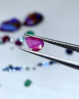 Pear-shaped ruby held by tweezers, profile view