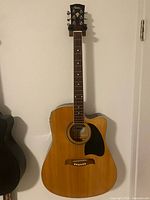 Full front view of Lyon cutaway acoustic-electric guitar hanging on wall