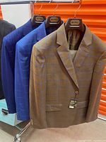 Three suits on hangers showing colors and patterns