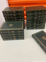 Multiple stacks of green Harvard Classics hardbacks on table