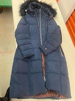 Full view of navy long puffer coat laid flat showing length and hood
