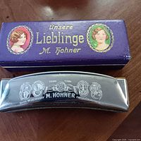 Top view of harmonica and lid of purple box showing brand and model