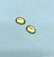 Pair of oval citrine gemstones on neutral background