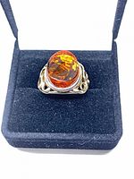 Ring front view in presentation box showing amber cabochon and filigree setting