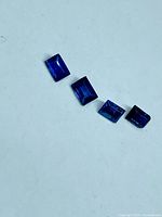 Four deep blue sapphire baguette stones on white background