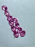 Ten pink oval cubic zirconia gemstones arranged for overview