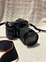 Front three-quarter view of Sony α200 camera with lens and strap visible