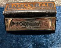 Hohner Pocket Pal harmonica resting on closed case, branding visible