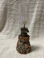 Full view showing glass chimney and shell-covered base