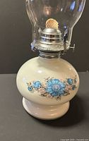 Full view of oil lamp showing floral ceramic base and burner