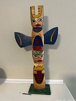 Front view of full totem pole showing carved figures, paint, Banff Canada mark.