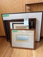 Group of six framed artworks stacked to show variety of sizes and frames