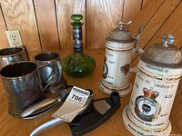 Group shot showing all items: ceramic steins, tankards, green bottle, garlic press, metal cutter