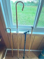 Four canes leaning against wall showing full length and handles