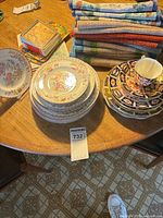 Stack of assorted china plates, teacup, placemats and coaster box on table