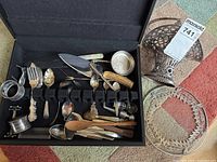 Overview of flatware case with Birks Regency forks, assorted utensils, napkin rings, pepper shaker, wooden pieces, glass platter, and decorative basket
