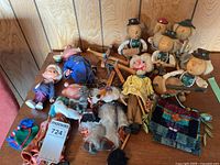 Group shot of all puppets, marionettes, wooden musician dolls, plastic doll and woven pouch on table