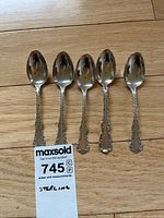 Five matching sterling silver teaspoons displayed side by side