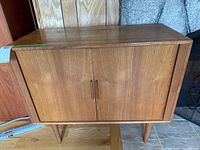 Front view of teak cabinet showing overall form, sliding doors, legs