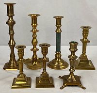 Group shot of all seven brass candlesticks showing varying heights and designs