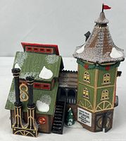 Front view of porcelain building showing twin smokestacks, roof detail, and snow accents