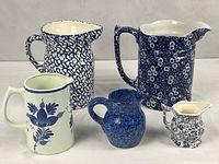Group shot of all five blue and white ceramic pitchers