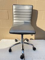 Front view of silver armless office chair on chrome rolling base