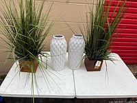 Entire lot: artificial plant in wooden planter and two white ceramic vases on table